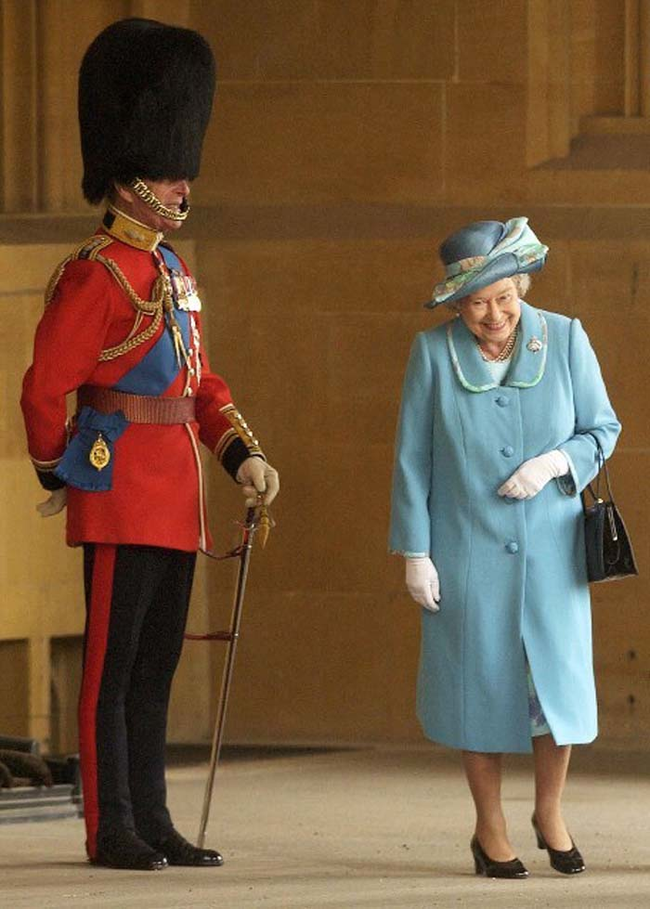 The Queen of England laughing at her husband dressed in his ceremonial uniform.